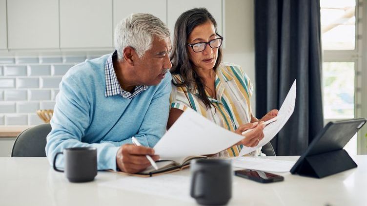 A couple reviews their retirement plan together from their kitchen.